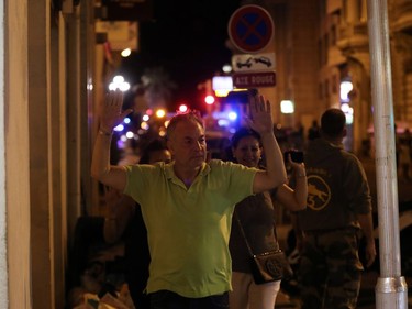 A man walks with his hands up as police officers carry out checks on people in the centre of French Riviera town of Nice, after a van that ploughed into a crowd leaving a fireworks display on July 14, 2016. At least 60 people are feared dead after a van drove into a crowd watching Bastille Day fireworks in the French resort of Nice on July 14, authorities said on July 15.