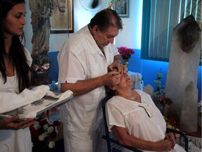 In this Feb. 23, 2012 photo, Medium Joao Teixeira de Faria, called Joao de Deus, or"John of God,"center, uses a knife to perform a visible spiritual surgery on Jane Sousa Simoes' eyes at the "Casa de Dom Inacio de Loyola" in Abadiania, in the state of Goias, Brazil. The "Casa de Dom Inacio de Loyola," or "The House of Saint Inacio de Loyola," was founded by popular faith healer Joao Teixeira de Faria in Abadiania, Brazil in 1978, where people seek cures for illnesses.