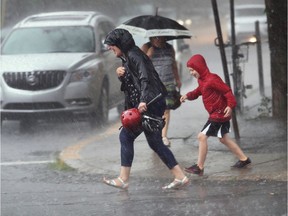 Marie-Claude Desforges and her son Justin Brunet took getting drenched in stride on Monkland Ave. in Montreal Thursday, July 14, 2016. The summer heat was broken temporarily by heavy rainfall.