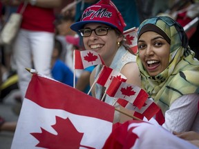Vanessa Reginato left, and Sabiha Begum sit on the sidewalk as they enjoy the Canada day parade in Montreal Friday, July 1, 2016.