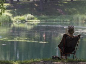 Anne-Catherine Gagne reads a book, while taking in the scenery, at the lake in Lafontaine Park. Montreal was hit with a second day of high heat and humidity  Wednesday July 13, 2016.