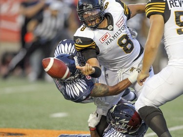 Hamilton Tiger-Cats quarterback Jeremiah Masoli tosses the ball underhand to a receiver while being tackled by Alouettes' John Bowman, bottom, and Winston Venable during a Canadian Football League game in Montreal, Friday, July 15, 2016.
