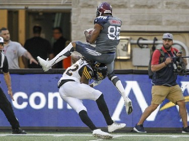 Alouettes' B.J. Cunningham comes down with the pass on top of Hamilton Tiger-Cats Courtney Stephen during Canadian Football League game in Montreal, Friday, July 15, 2016.
