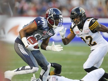 Alouettes Duron Carter heads upfield after breaking a tackle by Hamilton Tiger-Cats Rico Murray, bottom, as Cats Courtney Stephen pursues during Canadian Football League game in Montreal, Friday, July 15, 2016.