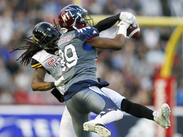 Alouettes Duron Carter catches pass in front of Hamilton Tiger-Cats Rico Murray during Canadian Football League game in Montreal, Friday, July 15, 2016.