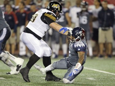 Alouettes quarterback Vernon Adams Jr. is knocked to the turf by Hamilton Tiger-Cats Michael Atkinson during Canadian Football League game in Montreal, Friday, July 15, 2016.  Atkinson was penalized for roughing the passer on the play.