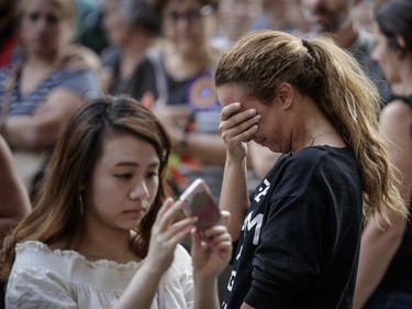 A woman is overcome with emotion during a vigil in memory of the victims of Thursday's terror attack in Nice, France, outside the French consulate in Montreal on Saturday, July 16, 2016.