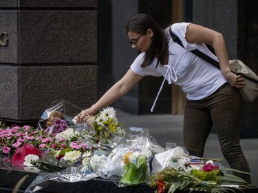 A woman places flowers on a memorial during a vigil in memory of the victims of Thursday's terror attack in Nice, France, outside the French consulate in Montreal on Saturday, July 16, 2016.