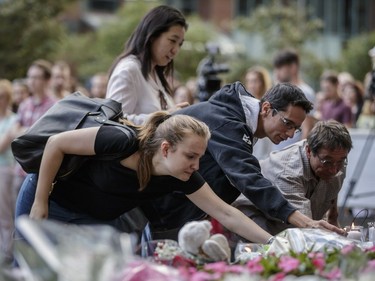 People leave flowers and candles at a memorial during a vigil in memory of the victims of Thursday's terror attack in Nice, France, outside the French consulate in Montreal on Saturday, July 16, 2016.