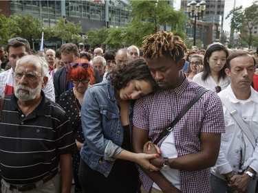 People pause during a minute of silence as they take part in a vigil in memory of the victims of Thursday's terror attack in Nice, France, outside the French consulate in Montreal on Saturday, July 16, 2016.