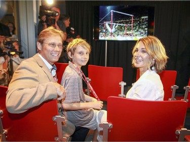 Nadia Comaneci, husband Bart Conner and son Dylan stop to watch a video of her competing in the 1976 Summer Olympics during a visit to the Olympic Park in Montreal on July 21, 2016, to mark the 40th anniversary of the 1976 Montreal Games.  They are sitting in seats from the old Montreal Forum, site of the gymnastics competition at the time.