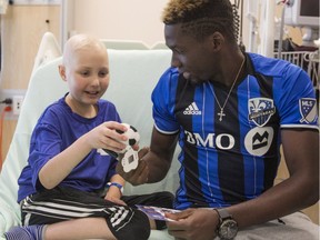 MONTREAL, QUE.: JULY 25, 2016 -- Montreal Impact player Ambroise Oyongo gives out miniature soccer ball to Montreal Children's Hospital patient, eleven year-old Jean-Gilles Gadoury, during the team's visit to the hospital on  Monday July 25, 2016. (Pierre Obendrauf / MONTREAL GAZETTE) ORG XMIT: 56745 - 0045