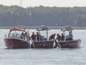 Firefighters and Canadian Coast Guard personnel coordinate during a search for possible victims on the St-Lawrence River near Parc de la Promenade-Bellerive, in Montreal, Wednesday July 27, 2016.  Authorities are searching after a pleasure boat collided with a cargo ship Tuesday night.