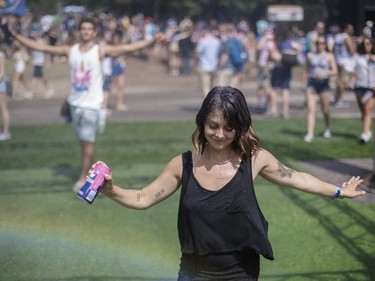 A reveller dances under a water mist on Day One of the Osheaga Music and Arts Festival at Parc Jean-Drapeau in Montreal on Friday, July 29, 2016.