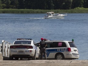 Montreal police officers stand guard next to body that was fished out of water near 36th Ave. in Pointe aux Trembles on Saturday, July 30, 2016.