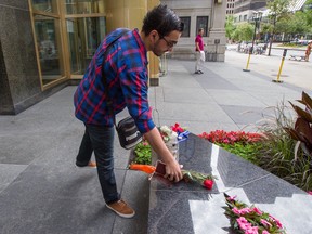 Abdel Raouph Chaabouni places flowers at a makeshift memorial set up outside the French consulate in Montreal, Friday July 15, 2016, to mourn the victims of Thursday's truck attack in Nice.