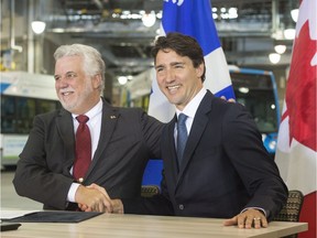 Prime Minister Justin Trudeau, right, shakes hands with Quebec Premier Philippe Couillard after signing an infrastructure announcement at a municipal bus depot Tuesday, July 5, 2016 in Montreal.