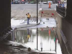 MONTREAL, QUE.: AUGUST 1, 2016 -- A worker takes pictures of a flooded underpass on St Laurent Boulevard at Van Horne, Monday August 1, 2016.  The flood was the resut of a broken water main that forced the closure of several blocks on St Laurent Boulevard to traffic for several hours.