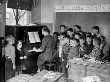 1957: Mrs. Craig is the only teacher and as such has an extra fondness for her 22 students. "They're with me all day," she points out. She plays piano as Gail Hinchcliffe, left, sings a solo. Plaid seems to be the theme in this classroom. Notice the plaid trim on the pants too.