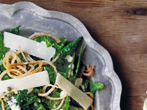 A caper dressing and parmesan cheese shavings top a kale salad. Deep-fried shallot rings are optional.