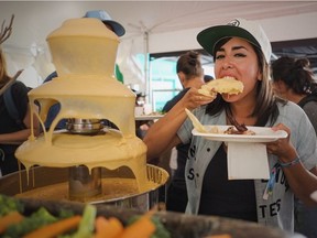 Montreal event organizer Dana Lluis experiments dipping a piece of fried chicken into the cheese fountain Saturday in Osheaga's Artist World food tent.