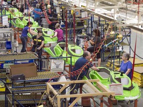 Employees work on the SeaDoo assembly line at the Bombardier Recreational Products plant Thursday, June 12, 2014 in Valcourt, Que. The maker of Ski-Doos, personal watercraft and three-wheel Spyder vehicles is evaluating whether to enter the two-wheel motorcycle business to help power its aggressive growth plans.