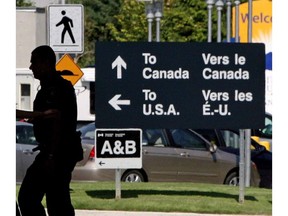 Canadian border guards are silhouetted as they replace each other at an inspection booth at the Douglas border crossing on the Canada-USA border in Surrey, B.C., on August 20, 2009. The Conservative government appears set to miss another target date for delivering a border tracking system that could stop homegrown terrorists from joining battles overseas.