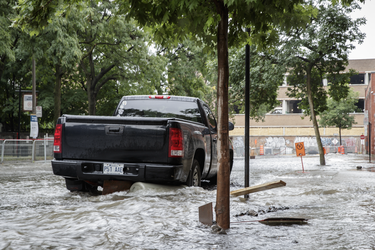 A vehicle is surrounded by water on Brewster avenue near the corner of St-Antoine street at the scene where a water main break caused flooding in the borough of St-Henri in Montreal on Saturday, August 13, 2016.