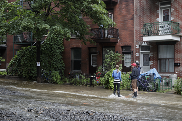 Residents look at the flooding on Brewster avenue near the corner of St-Antoine street caused by a water main break caused flooding in the borough of St-Henri in Montreal on Saturday, August 13, 2016.