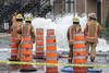 Firefighters look at a geyser of water caused by a water main break on the corner of St-Antoine street and Brewster avenue in the borough of St-Henri in Montreal on Saturday, August 13, 2016.