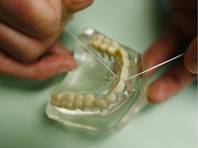 Dr. Wayne Aldredge, president of the American Academy of Periodontology, demonstrates how dental floss should be used in Holmdel, N.J. It's one of the most universal recommendations in all of public health: Floss daily to prevent gum disease and cavities. Except there's little proof that flossing works. When the federal government issued its 2016 dietary guidelines, the flossing recommendation had been removed, without notice.