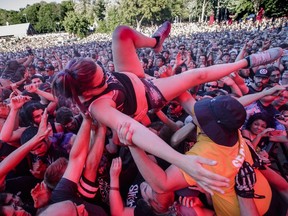 A woman crowd surfs during the performance by the American metalcore band Killswitch Engage on Day Two of the Heavy Montréal music festival at Jean-Drapeau Park in Montreal on Sunday, August 7, 2016. In promoting its 375th anniversary celebrations to Torontonians, Montreal is trading on its image as a party town.