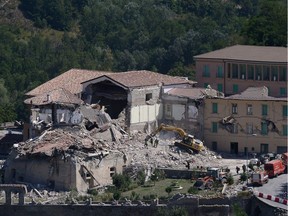 Rescue and emergency service personnel use an excavator to search for victims under the remains of a building at the damaged central Italian village of Amatrice, on August 25, 2016, a day after a 6.2-magnitude earthquake struck the region killing some 247 people.