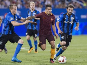 A.S. Roma's Juan Iturbe, centre, holds off a challenge from Montreal Impact's Wandrille Lefevre, left, and Hernan Bernardello during second half friendly soccer action in Montreal, Wednesday, August 3, 2016.