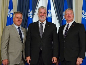 Quebec Premier Philippe Couillard poses with Quebec Transport Minister Laurent Lessard, left, and Quebec Minister of Forests, Wildlife and Parks Luc Blanchette, right, after a cabinet shuffle at the legislature in Quebec City on Saturday, August 20, 2016.
