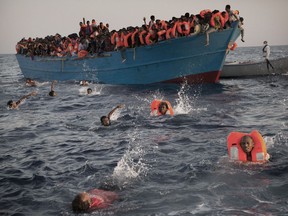 Migrants, most of them from Eritrea, jump into the water from a crowded wooden boat as they are helped by members of an NGO during a rescue operation at the Mediterranean sea, about 13 miles north of Sabratha, Libya, Monday, Aug. 29, 2016.