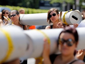 Demonstrators hold up tubes representing a pipeline as the World Social Forum holds a demonstration against the proposed Energy East pipeline. The demonstration tied up traffic in Montreal Aug. 11, 2016.