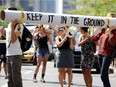Demonstrators hold up tubes representing a pipeline on René Lévesque Blvd. Aug. 11 to protest against the Energy East pipeline. Montreal hearings start Monday.