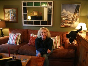 Tania Rollands, with her cat Charlotte, in her living room. Rolland has a great eye for colour and design. She has planned her cramped quarters very well and used vivid colours - brick red, grey blue, olive green, to create a dazzling palette that sets off her antiques, most of which she acquired in Nova Scotia. (Marie-France Coallier/ MONTREAL GAZETTE)