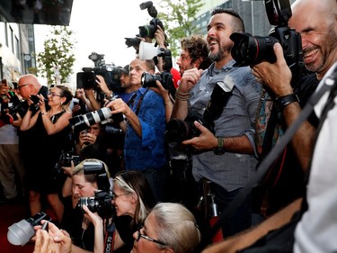 Photographers laugh with Émile Schneider as he jokes with Juliette Gosselin about it getting too hot on the red carpet outside the Imperial Cinema Thursday, Aug. 25, 2016 for the première of Quebec director André Forcier's Embrasse-moi comme tu m'aimes, the opening film of the Festival des films du monde.