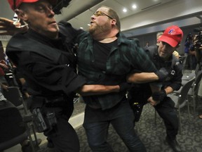 A protester is removed from the room where Montreal Mayor Denis Coderre was scheduled to speak at the National Energy Board public hearings into the Energy East pipeline project, Aug. 29, 2016.