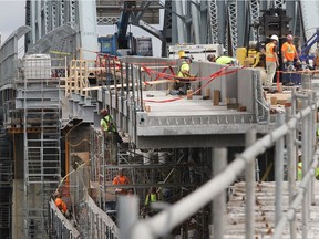 Mohawk workers from Kahnawake install a separated bike path on the Mercier Bridge spanning the St. Lawrence River on Tuesday, July 26, 2016. The last phase of major work to replace the deck on the federal section of the bridge was completed Aug. 14.