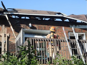 A firefighter looks at the roof structure as he stands on the balcony of a burned duplex on June 17, 2016.