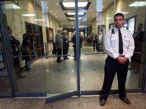 A security guard stands guard outside main door of the administrative offices of the McGill University Health Centre on Guy St. in Montreal on the morning of Sept. 18, 2012. UPAC, the anti-corruption squad, were conducting a raid in the offices.