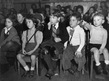1948: Children at Royal Vale school watch a funny movie during their school carnival. No danger of the boy in the middle being cold with that complicated outfit.