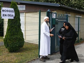Muslim worshippers walk past a poster reading "Mourning Mosque" after the friday prayer at the Yahya Mosque, in Saint-Etienne-du-Rouvray, Normandy, France, Friday, July 29, 2016. Four days after the hostage taking in Saint-Etienne-du-Rouvray, officials and worshippers of the Muslim community paid tribute to Priest Jacques Hamel and the Christian community.