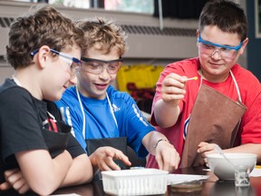 A trio of boys from St. George’s Elementary School, having donned aprons and safety goggles, perform a science experiment in the classroom.  (Photo courtesy of St. George’s School of Montreal)