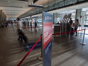 Passengers and employees approach mostly empty Delta Airlines counters at Trudeau International Airport in Dorval, Monday August 8, 2016, as the airline tries to get its computer systems back online.  Their computer systems went down early Monday causing flight cancellations and delays worldwide.