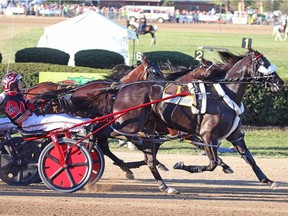 Montrell Teague drives Wiggle It Jiggleit, foreground, across the finish line to win the 2015 Little Brown Jug harness race at the Delaware County Fairgrounds in Delaware, Ohio.
