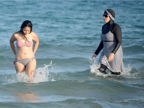 Tunisian women, one (R) wearing a "burkini", a full-body swimsuit designed for Muslim women, swim on August 16, 2016 at Ghar El Melh beach near Bizerte, north-east of the capital Tunis.